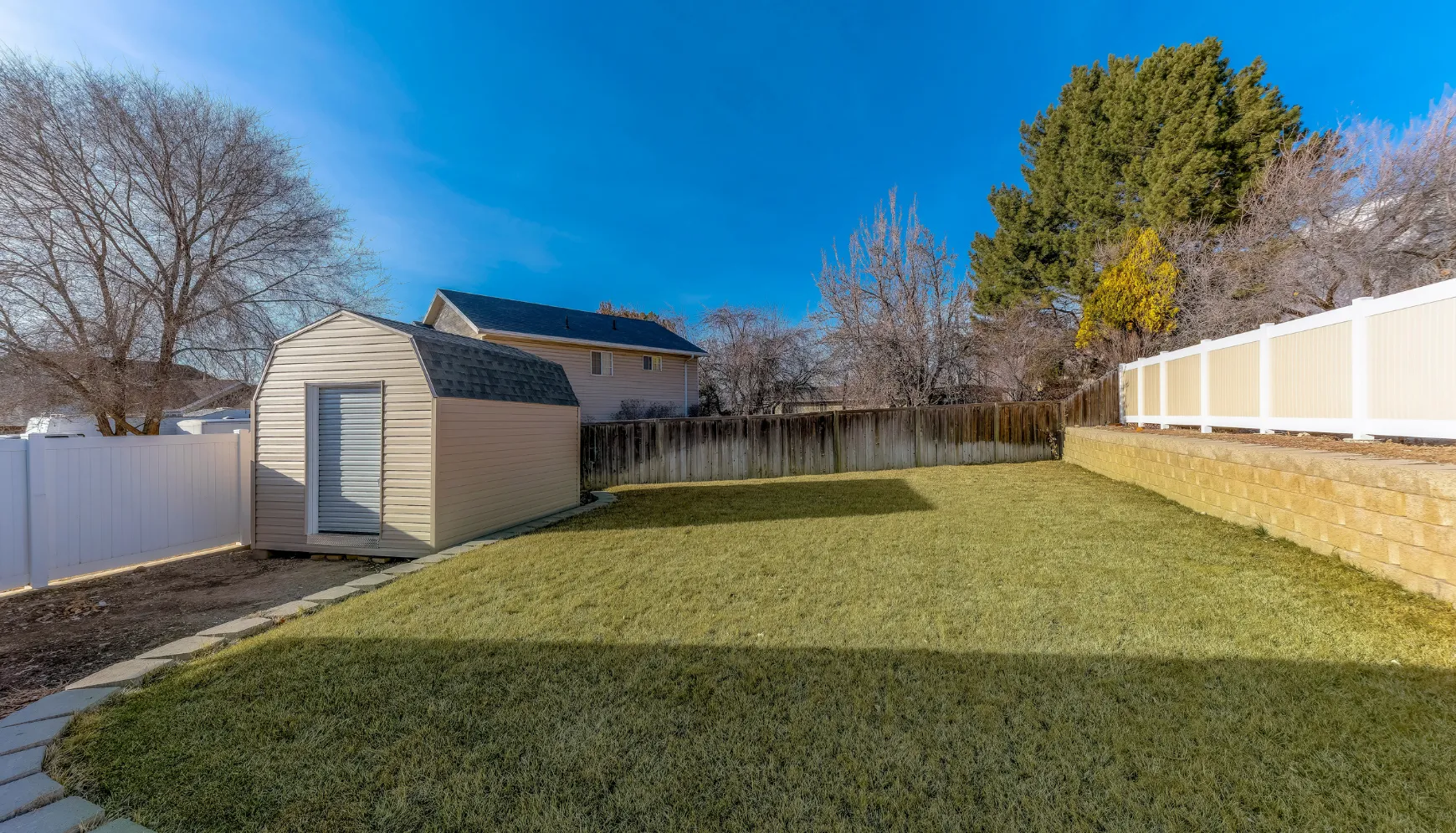 Backyard before detached ADU construction showing lawn and small storage shed